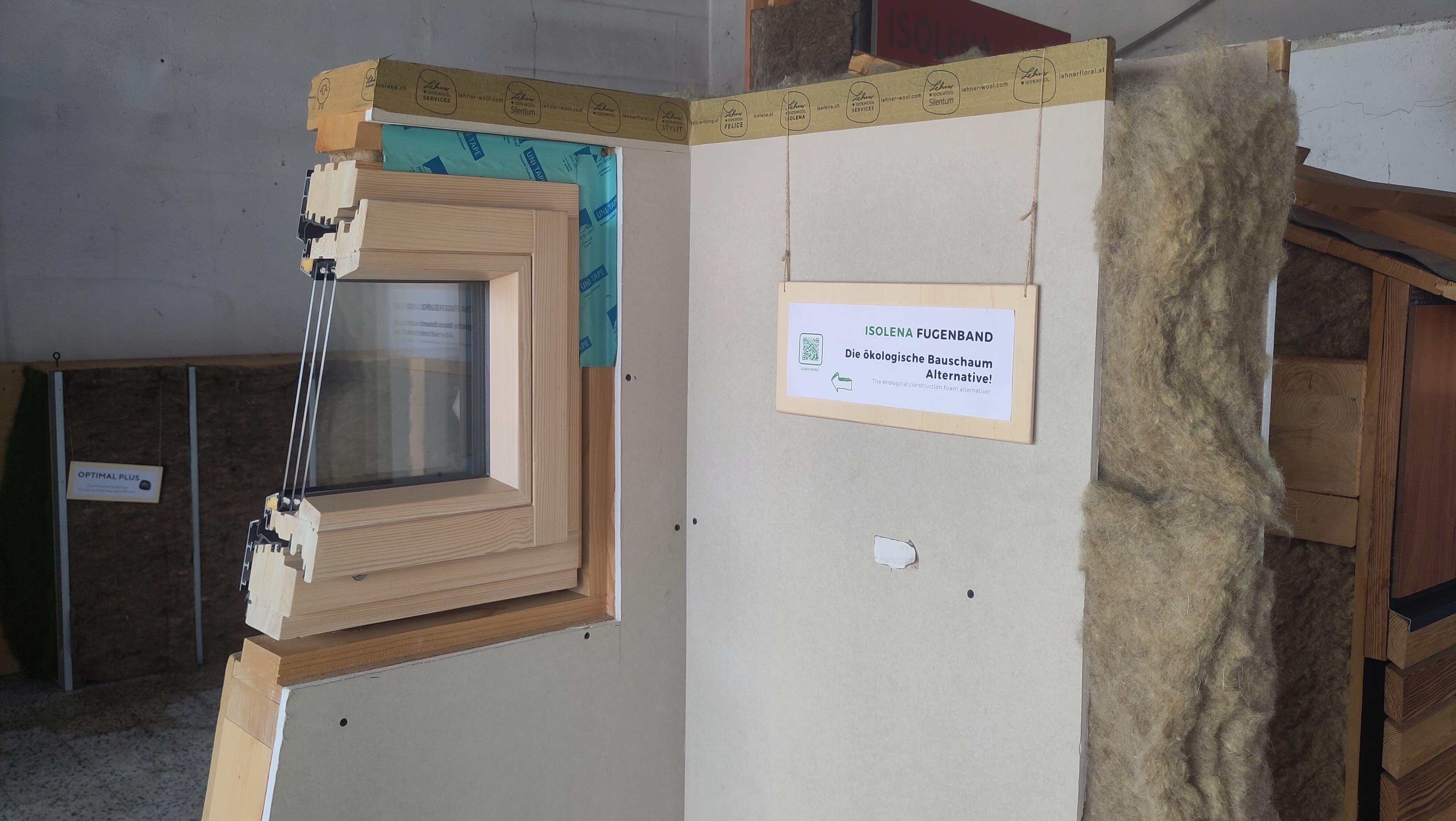 Doorsnede van een houten raamkozijn met ecologische schapenwolisolatie en blauwe afdichtingstape in een wand.